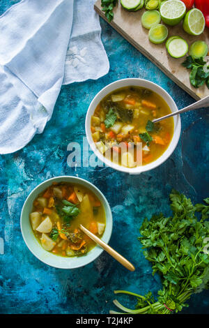 Minestrone, auf die Schüssel und der Mixbecher, auf einer konkreten blau getönten Hintergrund Stockfoto