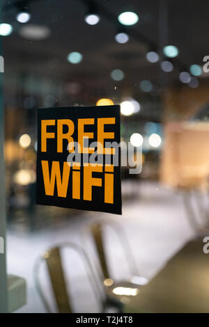 Gelb kostenloser Wi-fi-Zeichen auf das Fenster in ein Cafe mit wunderschönen 1.4 aperture Bokeh - Einkaufszentrum Stockfoto