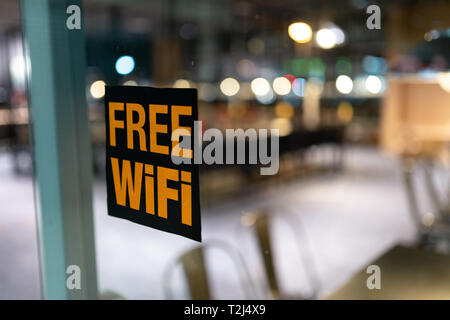 Gelb kostenloser Wi-fi-Zeichen auf das Fenster in ein Cafe mit wunderschönen 1.4 aperture Bokeh - Einkaufszentrum Stockfoto