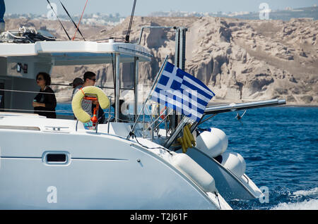 Eine griechische Flagge weht im Wind auf einer Bootsfahrt um Santorini, Griechenland. Stockfoto