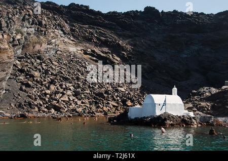 Die kleine Kirche des Heiligen Nikolaus thront auf Palaia Kameni, einer kleinen Insel in der Caldera von Santorini. Stockfoto