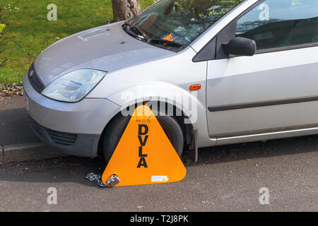 Unversteuerten Fahrzeug fahruntüchtig am Straßenrand durch einen gelben DVLA Klammer, für die Entrichtung der Kraftfahrzeugsteuer Stockfoto