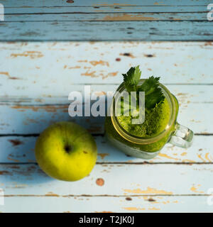 Gesunde detox Green Apple und Gemüse Saft in Mason jar mit Sellerie auf der Oberseite. Es dient auf Holz- Blue vintage Hintergrund Stockfoto