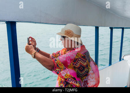 Surat Thai, Thailand - Januar 24, 2018: Touristen, die auf die Fähre nach Koh Samui und Koh Phangan Inseln. Alte Frau, die auf dem Deck untersagen Stockfoto