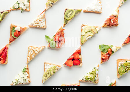 Blick von oben auf die leckeren Toast mit Obst, Gemüse und Schinken isoliert auf weißem Stockfoto