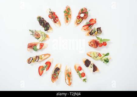 Blick von oben auf die runden Rahmen aus traditionellen italienischen Bruschetta mit Lachs, Schinken, Kräuter und verschiedene Früchte und Gemüse Stockfoto