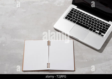 Flach, Ansicht von oben stilvolle Büro tisch Schreibtisch. Arbeitsbereich mit Laptop, Tagebuch auf grauem Hintergrund. Stockfoto