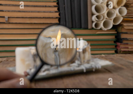 Eine alte Kerze durch ein Vergrößerungsglas betrachtet. Kerze Feuer in einem großen Vergrößerung gesehen. Der dunkle Hintergrund. Stockfoto