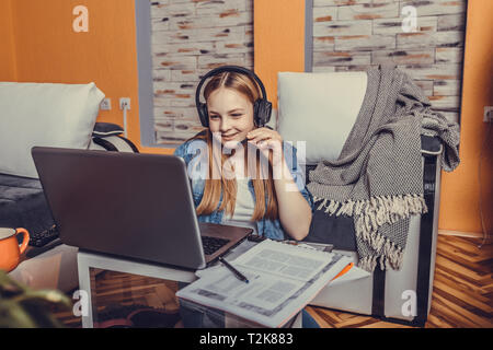 Glückliche junge jugendmädchen in Kopfhörer sprechen auf Laptop Notizen, Mädchen Schüler sprechen von Videokonferenz, Lehrerin Trainer Stockfoto