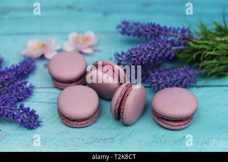 Französische Macaron Cookies Dessert rosa Flieder auf einem dunklen schwarzen Hintergrund mit rosa Blüten Lavendel Stockfoto