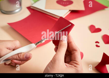 Frau schneidet aus rotem Filz Herzen, hausgemachte Handwerk für Valentinstag, Hand Kreativität, Ansicht von oben Stockfoto