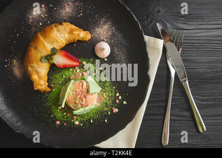 Cherry und Apfelstrudel serviert mit einer Kugel Vanilleeis auf einem keramischen schwarze Platte. Blick von oben. Stockfoto