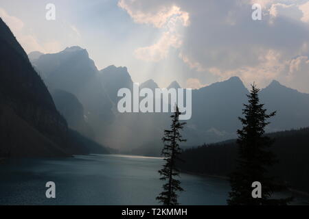 Sonnenlicht, das durch die Wolke auf wunderschönen Berggipfel, Bäumen und einem See Stockfoto