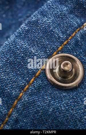 Nahaufnahme aus blauem Denim-Stoff, das ein Fadenmuster mit Warp- und Schussmuster sowie orangefarbene Nähte zeigt. Genähte Linie, Stichlinie. Stockfoto