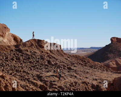 CALAMA, CL-CA. OKT 2018 - stehendes Mädchen auf einem Felsen in der unglaublichen roten Felsen des Mondes Tal (Valle de la Luna) in der Nähe von San Pedro de Atacama an Su Stockfoto