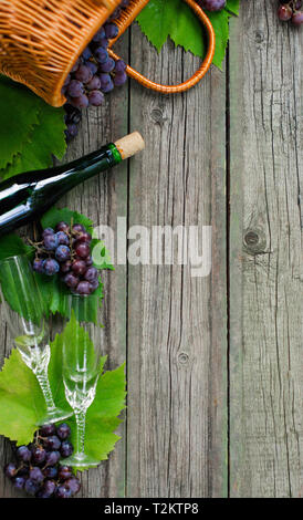 Weinflaschen mit Trauben, Korb, zwei Weingläser auf rustikalen, mit Holz. Vertikale Wein Hintergrund. Stockfoto