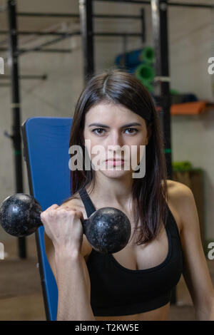 Das Mädchen ist mit Hanteln in der Turnhalle eingerückt Stockfoto