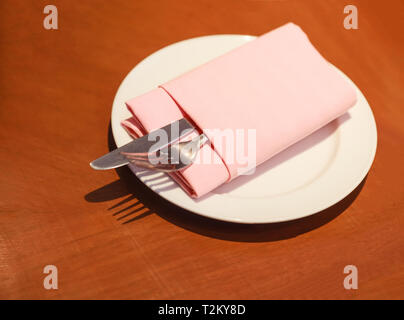 Pastellfarben tuch Serviette (Serviette) Falten mit Besteck (Messer, Gabel, Besteck) in Weiß Platte auf dem hölzernen Tisch bereit, bereit für den Kunden nicht zu verwenden. Stockfoto