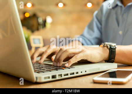 Zugeschnittenes Bild des Geschäftsmanns, der auf seinem Laptop in einem Café Stockfoto