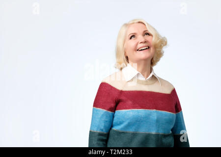 Gerne fröhliche ältere blonde Frau auf positive Nachrichten mit charmanten Lächeln freuen. Großmutter in Glück für Ihre Kinder Stockfoto