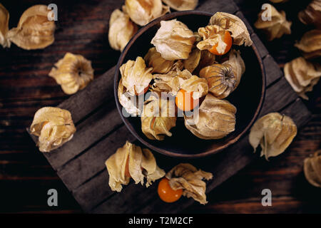 Gelbe Kap Stachelbeeren Obst in der Schüssel auf Holz Textur Stockfoto