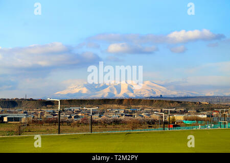 Foto Panorama einer schönen Berg frühling landschaft mit schneebedeckten Bergen und der Stadt Stockfoto