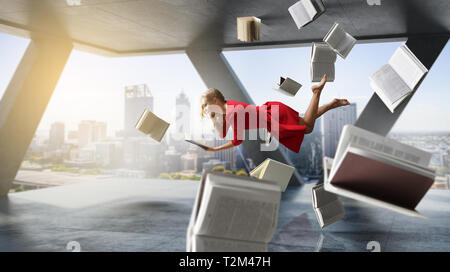 Entspannt Frau levitates in Raum voller Fliegen Bücher. Mixed Media Stockfoto
