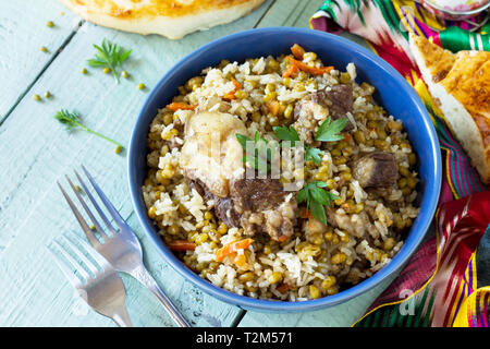 Die arabische Küche. Veranstaltungen Ramadan. Im Nahen und Mittleren Osten Mashkichiri (Brei von Reis, Rind und mung Bean) auf hölzernen Tisch. Ansicht von oben flach Hintergrund. Stockfoto