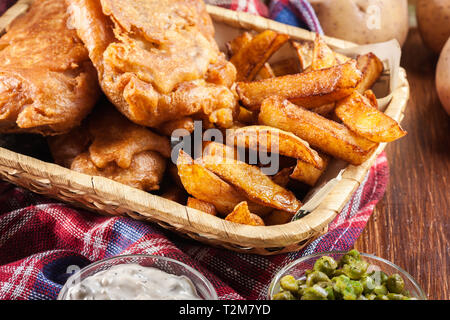 Traditionelle Fisch im Bierteig und Chips auf Korb serviert. Stockfoto