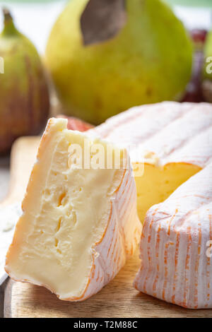 Rundes Stück französischer Käse Fleur Rouge aus Kuhmilch hergestellt als Dessert serviert mit frischen Feigen und Birnen Nahaufnahme Stockfoto