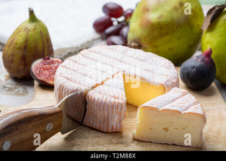 Rundes Stück französischer Käse Fleur Rouge aus Kuhmilch hergestellt als Dessert serviert mit frischen Feigen und Birnen Nahaufnahme Stockfoto