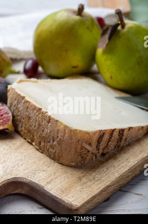 Stück französischer Käse Tomme de Brebis aus Schafsmilch hergestellt als Dessert serviert mit frischen Feigen und Birnen Nahaufnahme Stockfoto