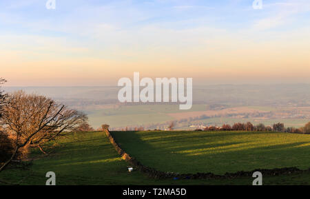 Panoramablick von chevin Park mit Blick auf den kleinen Yorkshire Markt Stadt Otley in die dunstige Ferne, als die Sonne. Stockfoto