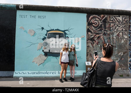 Berlin. Deutschland. Touristen posieren für Fotos vor der berühmten Birgit Kinders Wandbild 'Test der an der Berliner Mauer Rest" an der East Side Gallery. Stockfoto