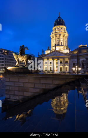 Leuchtet die Neue Kirche (Deutscher Dom, Deutsche Kirche oder Kathedrale) und eine Statue vor dem Konzerthaus Berlin am Gendarmenmarkt in der Abenddämmerung. Stockfoto