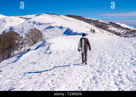 Ohr der Frau zu Fuß auf schneebedeckten Feld gegen Sky Stockfoto