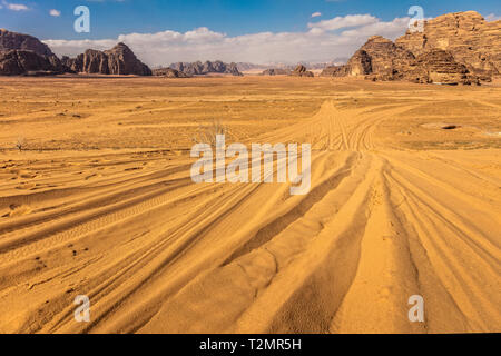 Spuren von Off-Road-Reifen auf dem Sand der Wüste Wadi Rum in Jordanien, Rocky Mountains im Hintergrund. Reisen und Abenteuer. Stockfoto
