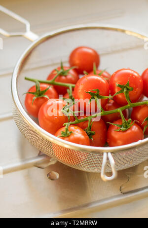 Schönen frischen biologischen Strauchtomaten waschen, in einem Sieb auf der Abtropffläche mit einem Marienkäfer Stockfoto