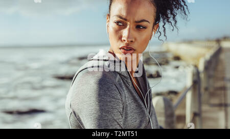 Sportliche junge Frau, die auf der Promenade und dem Strand entfernt. Läuferin Ausruhen nach einem Lauf. Stockfoto