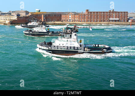 Drei SERCO GMBH, leistungsfähige Schlepper unterstützen die Royal Navy Flugzeugträger HMS QUEEN ELIZABETH als Sie geht Fort Blockhaus, Gosport. Portsmouth Harbour. Stockfoto