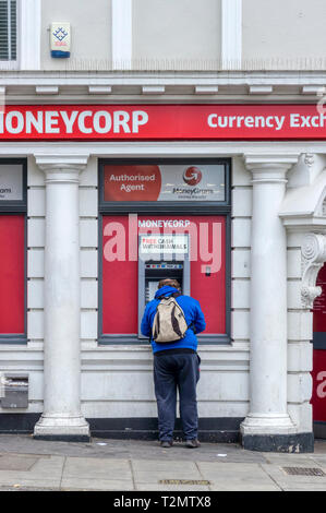 Mann mit MoneyCorp kostenloser Bargeldbezug Maschine. Stockfoto