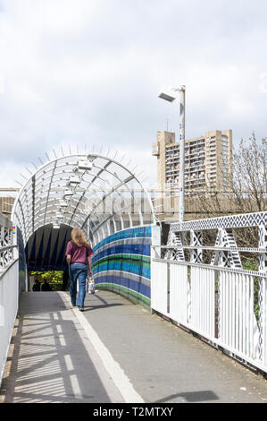 Eine Person auf einer Fußgängerbrücke über eine Bahnstrecke und Fußweg unter Westway, die A 40, im Westen von London. Stockfoto