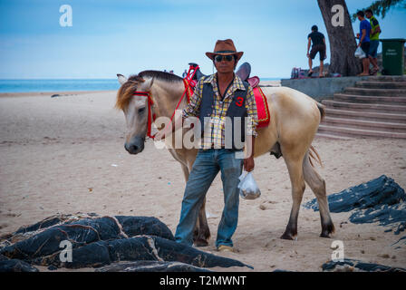 Songkhla, Thailand - Okt 2015: Mann mit einem Pferd an den populären Samila Strand posiert, Thailand Stockfoto