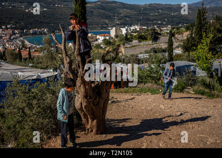 Vathy, Griechenland. 25 Mär, 2019. Flüchtling spielen die Kinder auf einen Baum im Camp auf der griechischen Insel Samos. Rund 4500 Flüchtlinge und Migranten leben hier. Sie wurden gezwungen, um die Insel zu vereinbaren so genannte Hotspot, einem ehemaligen Gefängnis, das sich hinter der Stahl Zäune mit Stacheldraht bewehrt, bietet Platz für 650 Personen. Credit: Angelos Tzortzinis/dpa/Alamy leben Nachrichten Stockfoto