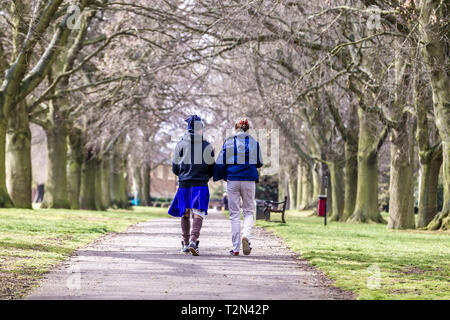 Northampton. 3. April 2019. UK Wetter: Abington Park. Ein paar Spaziergang durch die Allee der Bäume, die zu Park Avenue South in den späten Morgen Sonnenschein, mit der Prognose für Donner und Beleuchtung später am Nachmittag. Credit: Keith J Smith./Alamy leben Nachrichten Stockfoto