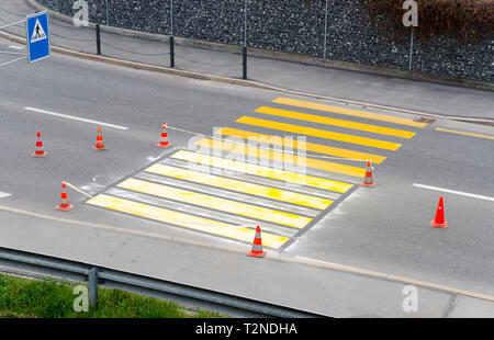 Abgesperrt frisch Fußgängerzone Zebrastreifen mit leuchtend gelben Farbe für Straße und Verkehr Sicherheit in einem Schweizer Dorf gemalt Stockfoto