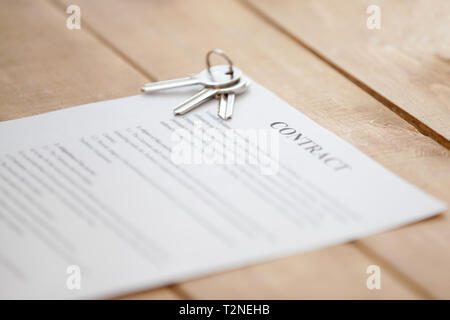 In der Nähe der Tasten liegen auf einem vertragsdokument Papier auf einem Holztisch. Neue Wohnung oder Haus erfolgreich Immobilien, kauf verkauf, vermietung und t Stockfoto