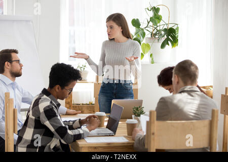 Fünf Unternehmer im Seminar im Büro boardroom Junge schwere zuversichtlich Chef Trainer weibliche Ständigen argumentieren und gestikulierte mit diversen nicht einverstanden Stockfoto