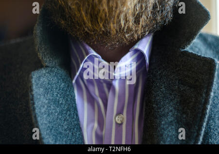 Nahaufnahme der angehobenen Revers in einem grauen Mantel auf Bärtiger Mann im gestreiften Hemd. Ohne Krawatte Business Kleidung und Zubehör Stockfoto