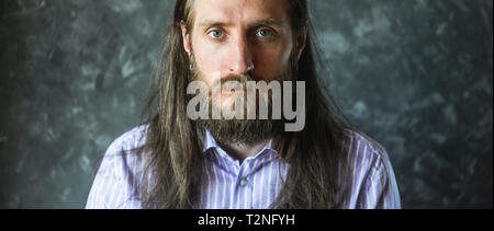 Mode Portrait eines bärtigen Mann im gestreiften Formale Shirt mit Langen fließenden Haar. Informelles Konzept. Filmische Erntegut Stockfoto